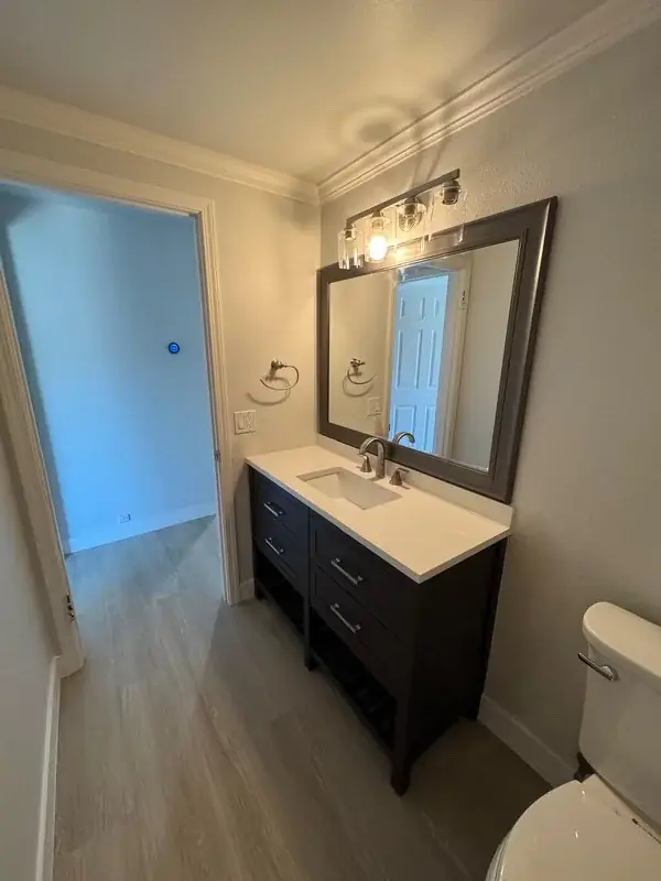Espresso vanity with framed mirror and sconce lighting