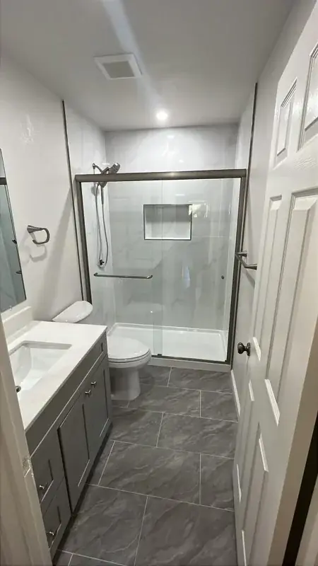 Bathroom with marble-look sliding glass shower and gray vanity