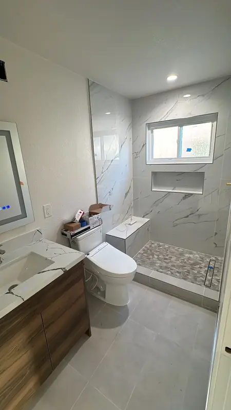Marble-tile walk-in shower with pebble floor and floating wood vanity
