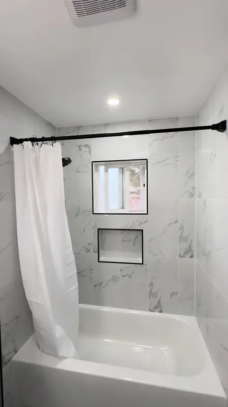 White marble tub-and-shower alcove with recessed niche