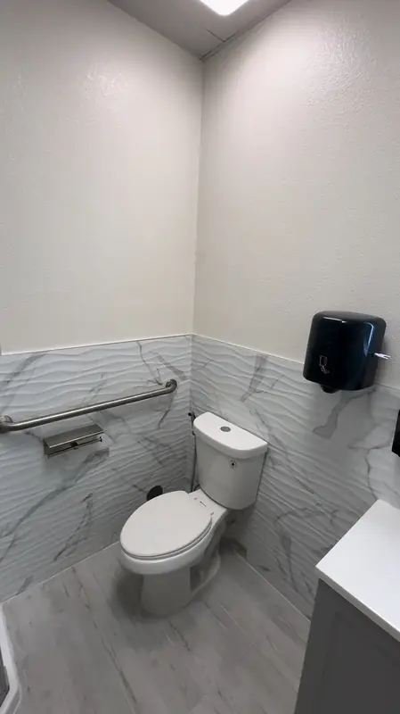 Commercial restroom with marble-look wainscot and grab bar