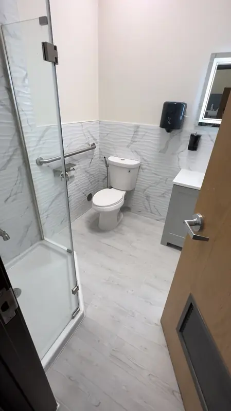 Commercial restroom with glass shower and gray vanity